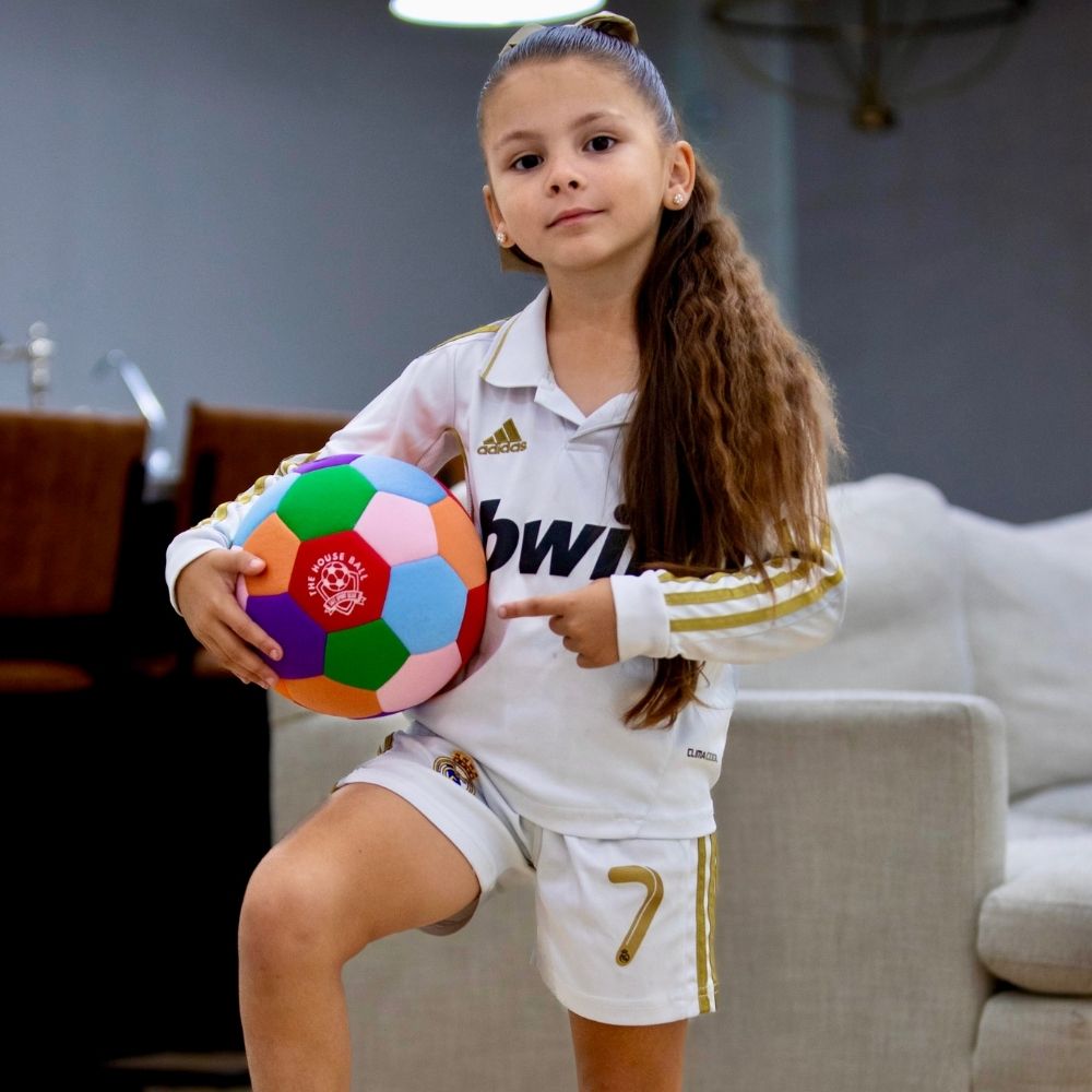 Young girl in sports uniform holding The House Ball