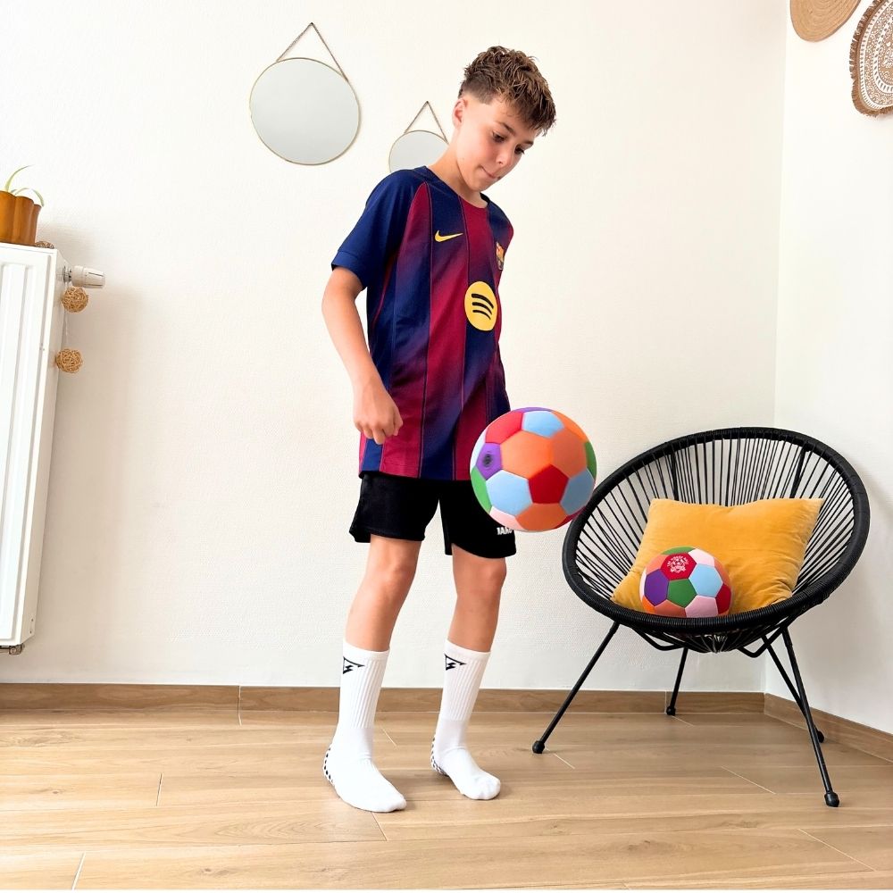 Young boy kicking The House Ball indoors in a living room.