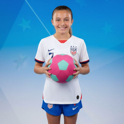 Young girl in a soccer uniform holding The Pink House Ball against a blue background