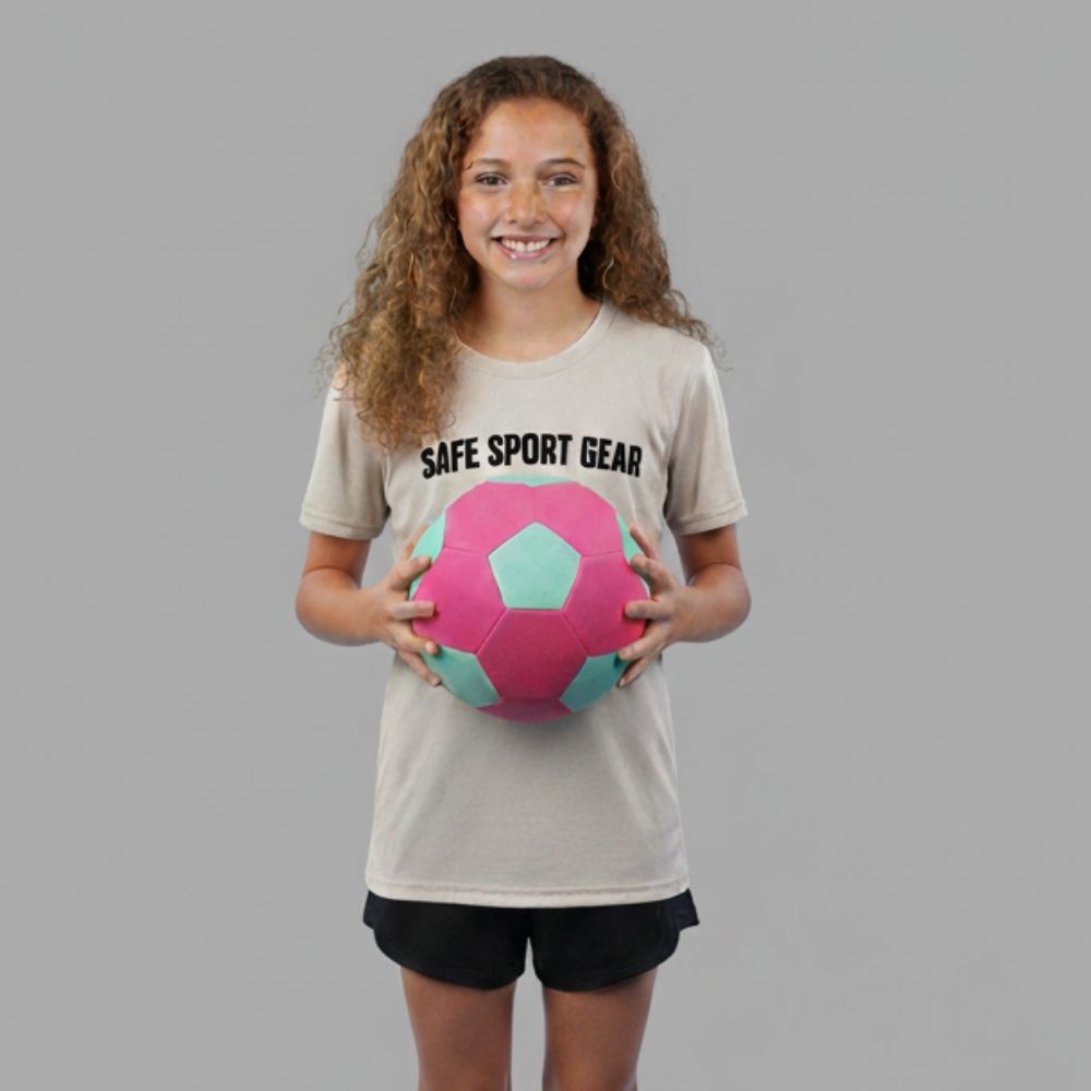 Girl wearing a 'Safe Sport Gear' t-shirt holding The Pink House Ball on a gray background