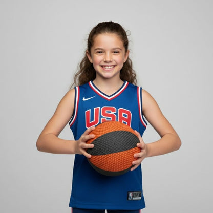 Young girl wearing a USA basketball jersey holding a HouseHoops Basketball against a gray background