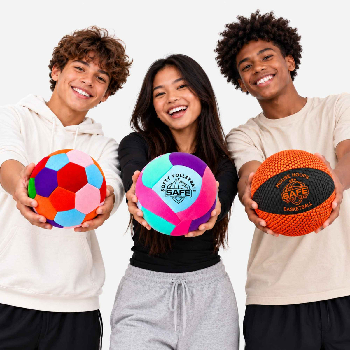 Three smiling young athletes hold colorful houseball, volleyballs and basketballs against a clean white studio background. The center child holds a bright pink, purple, and teal ball with 'SAFE Sport Gear' logo printed on it.