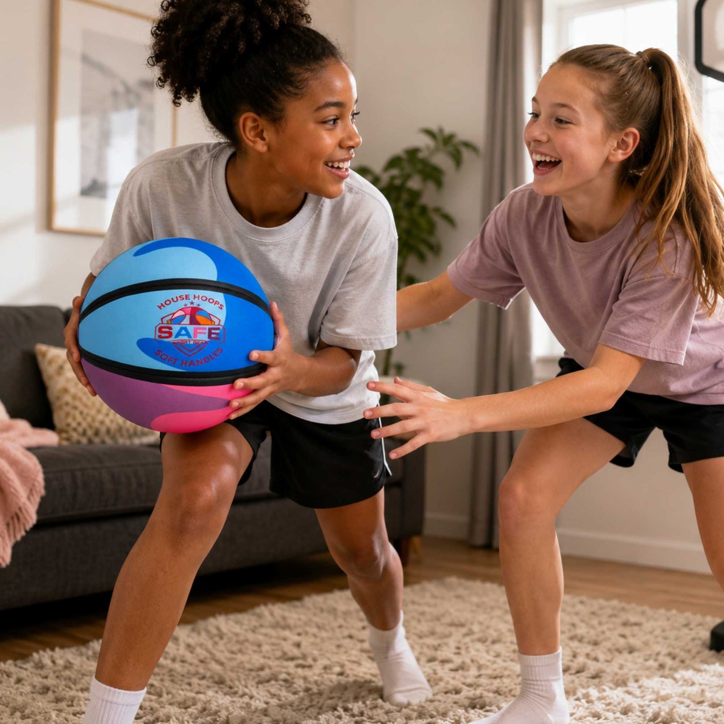 Two young girls playing with HouseHoops basketball - Soft Handles in a living room.