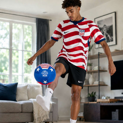 Person in a red and white striped soccer jersey kicking a House Ball - USA in a living room.