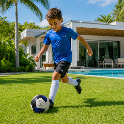 Child playing soccer with a Pace Raptor Size 5 Soccer Ball - Blue on a grassy lawn with a pool and modern house in the background