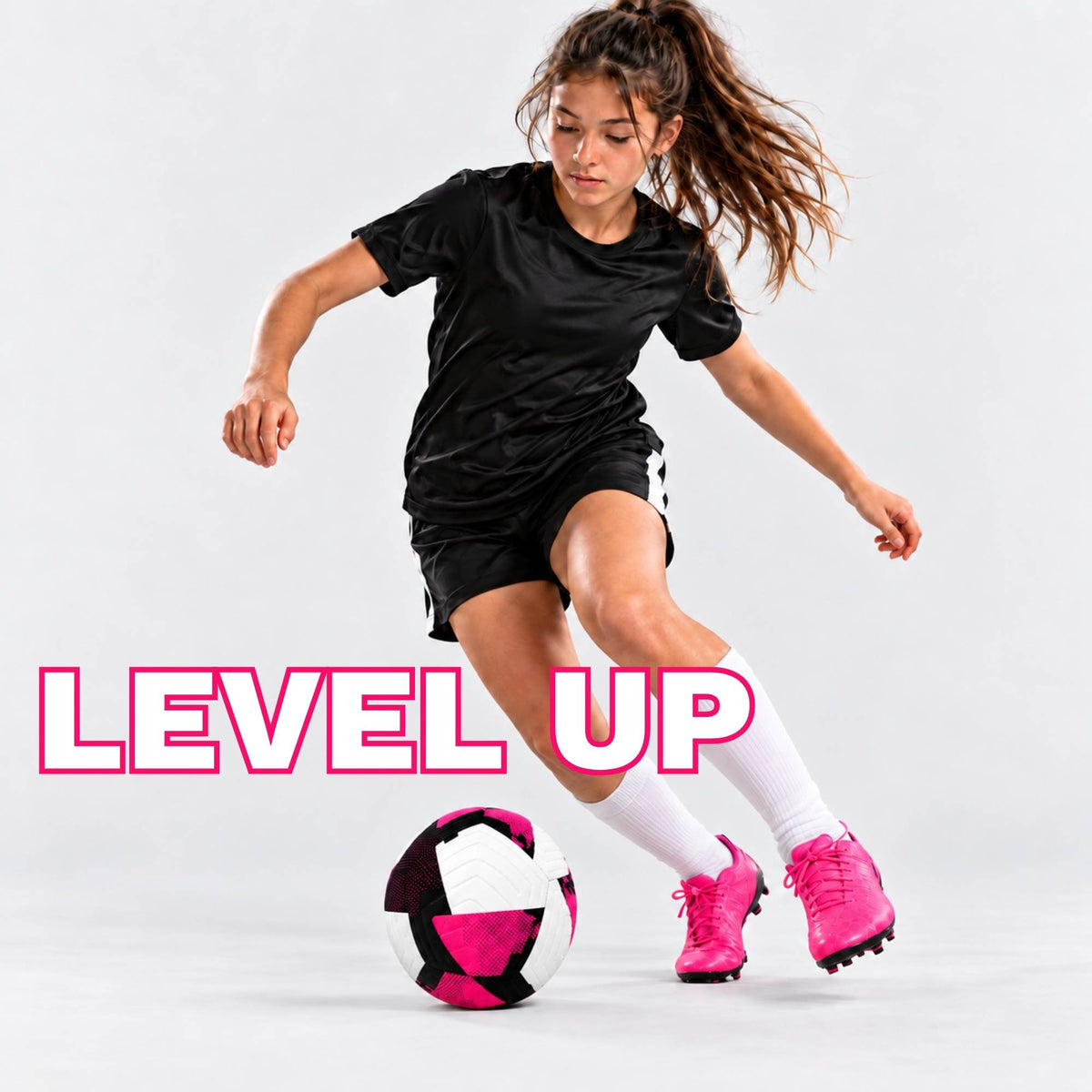 A female soccer player in a black athletic uniform and white socks kicks a pink, black, and white soccer ball on a light gray studio background, with the text 'LEVEL UP' in pink outlined letters across the lower left.