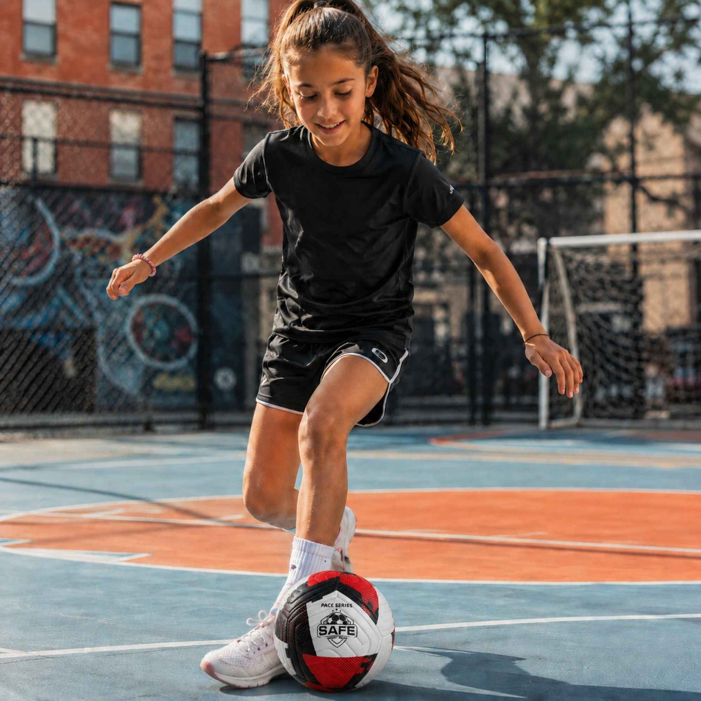Child playing with a Pace Raptor Size 4 Soccer Ball - Red on an outdoor court