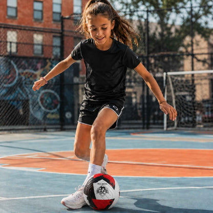 Child playing with a Pace Raptor Size 4 Soccer Ball - Red on an outdoor court